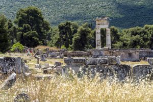 Epidaurus, Greece - May 18, 2025: Remains of the Temple of Asclepius in Epidaurus, showcasing classical Greek architecture with tall stone columns against scenic hills.